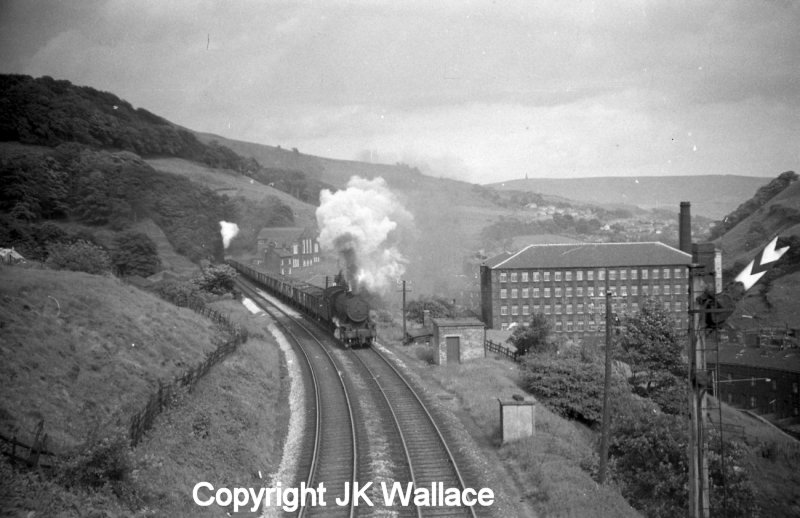 A freight train bound for Copy Pit and Rose Grove hauled by WD 90412 and banked by Crab 42727 emerge from Kitson Wood Tunnel and cross Lydgate viaduct, and are seen approaching Knotts Road bridge.