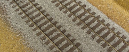 The ballast is gentle brushed clear of the sleepers with a paint brush.