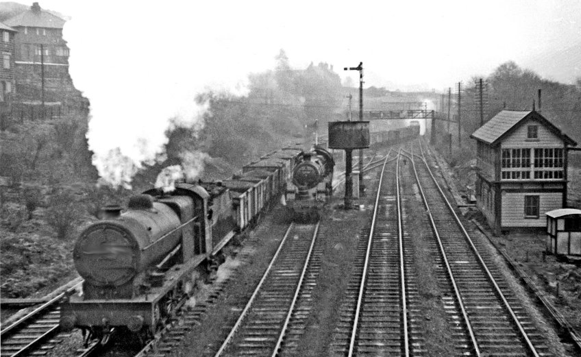 Ben Brooksbank's photo shows the view eastward on a wet day, towards Sowerby Bridge, Wakefiled etc.: ex-L&Y Calder Valley main line. The Class J coal train has emerged from Horsfall Tunnel and is turning onto the line to Burnley, passing a BR Standard 4MT 4-6-0 75049. At its head is a typical LMS Fowler 7F 0-8-0, No. 49566 (built 1929, withdrawn 9/57). The lines on the right go to Todmorden, Rochdale and Manchester.