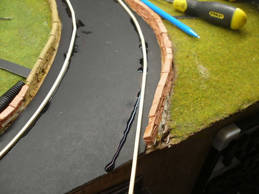 Construction of a 4mm model road: Step 8 The Superglue is applied along the line of the kerb, and then the kerb bent and held into place util the glue had set.