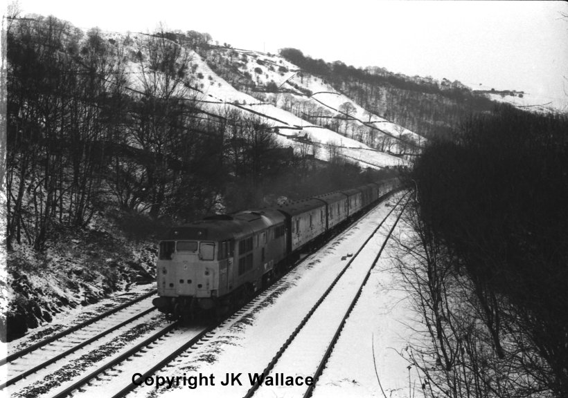 Class 31 No. 31437 passing Eastwood on the Calder Valley line with the Newcastle-Red Bank empty news vans. 1986.