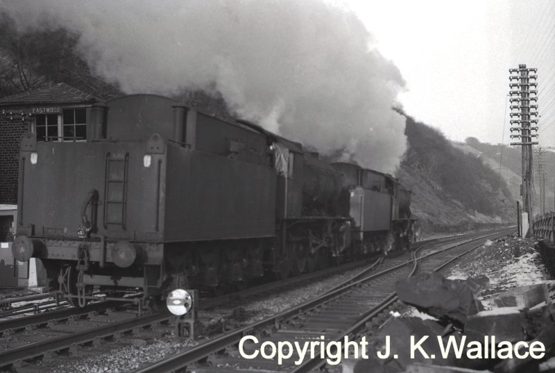 A pair of WD Austerity 2-8-0s running light steam past Eastwood signal box heading towards Healey Mills in 1965. Note the tarpaulin filling the fireman's side window and filling the gap between cab and tender.