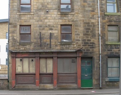 Front of 80 Halifax Road, Todmorden showing old shop front. Door has anti-flood board slotted in. 