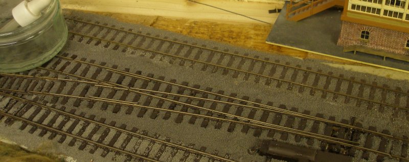 Ballast brushed around the sleepers of the PECO Streamline Bullhead OO scale Code 75 Unifrog point (turnout) being moistened with IPA after it had been laid on the Hall Royd Junction model railway layout.