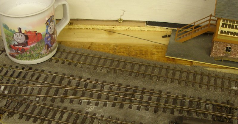 Dilute PVA glue is droppered onto the ballast brushed around the sleepers of the PECO Streamline Bullhead OO scale Code 75 Unifrog point (turnout) after being moistened with IPA after it had been laid on the Hall Royd Junction model railway layout.